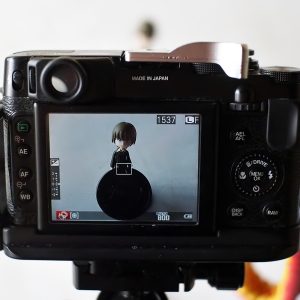 在线屏幕检测主编沈砚舟坐在暗室中，面前显示器显示灰阶测试图，他手持色卡比对屏幕色彩表现